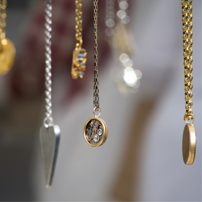 Close up of several hanging gold and titanium pendants on necklaces