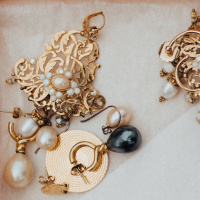 A close up photo of several copper and pearl earings on a white background